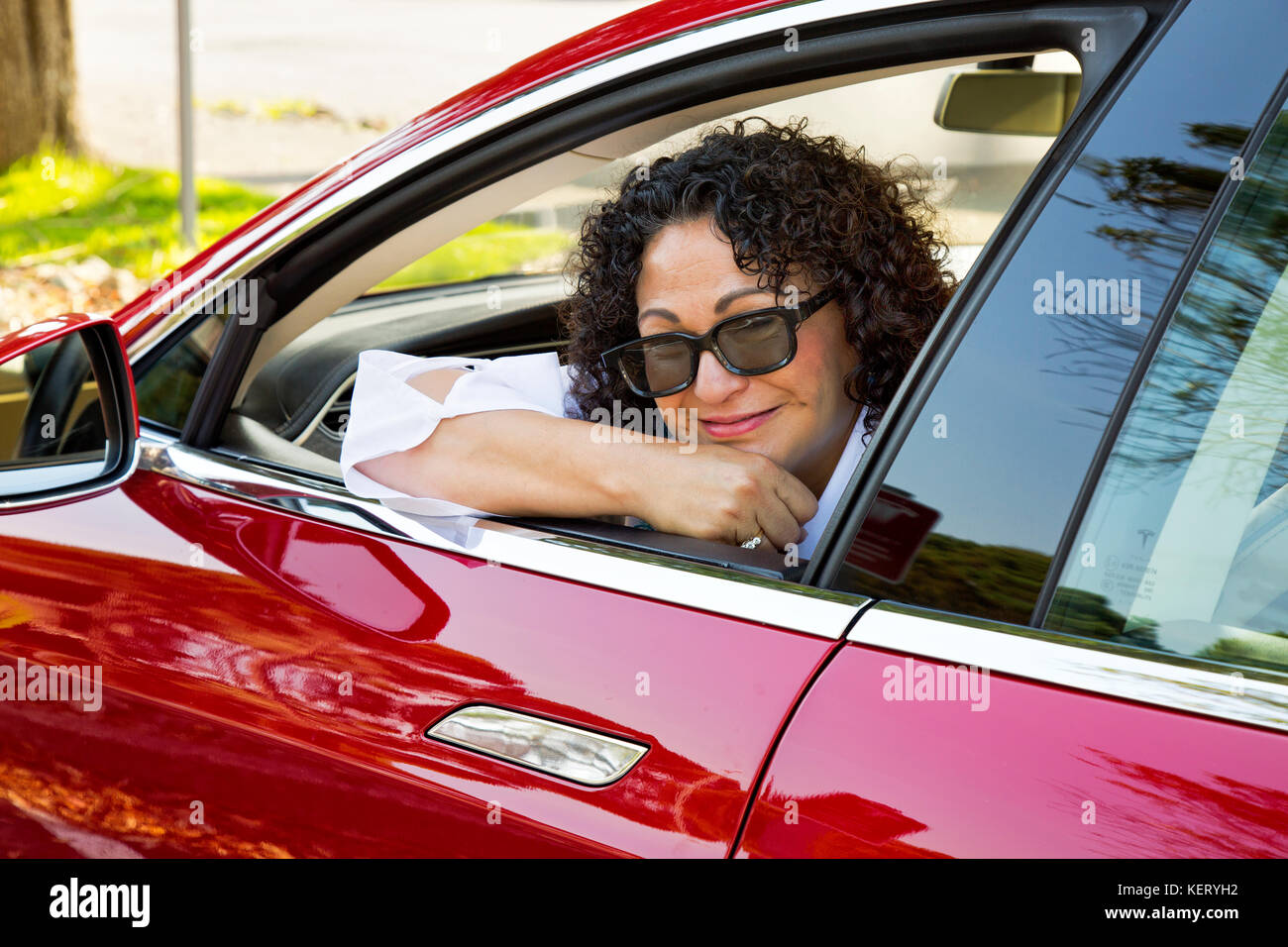 Sorridenti Tesla 'S' Sedan proprietario femmina, Supercharger stazione. Foto Stock