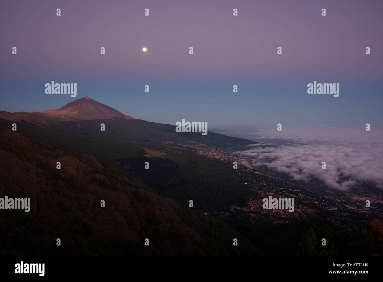Vista notturna di commercio vento nuvole sulla valle di Orotava con il Pico del Teide nella parte anteriore del sunrise, dietro la palma Foto Stock