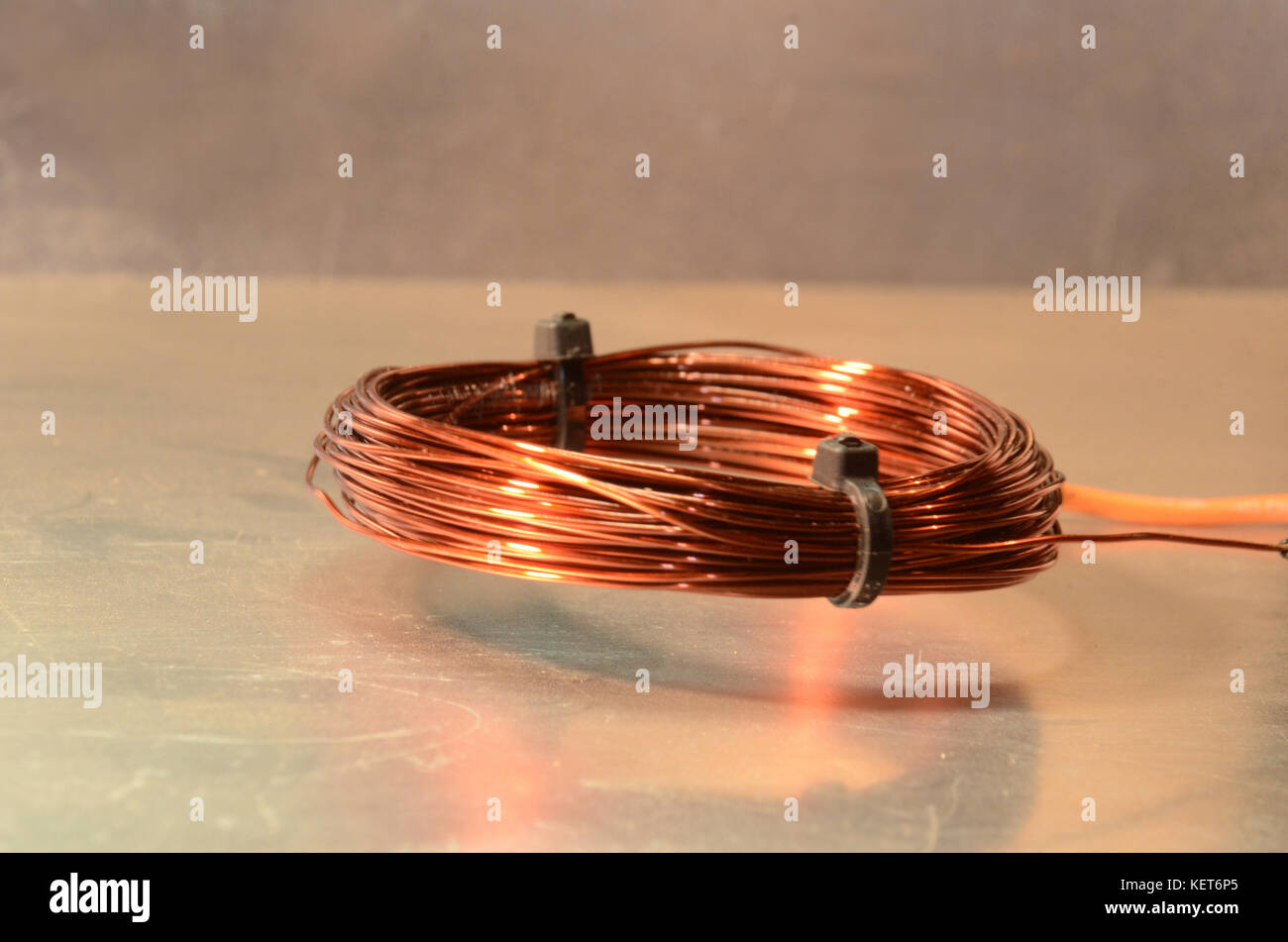 Una bobina alimentata con corrente alternata passa sopra una piastra metallica. Foto Stock