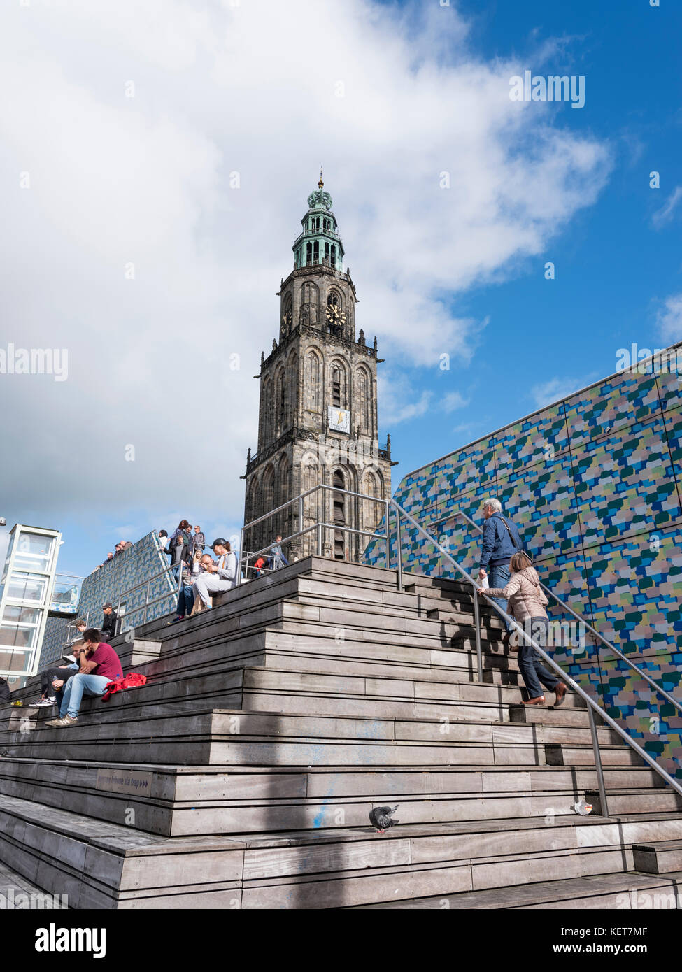 Persone sedersi sui gradini nei pressi della piazza centrale di fronte a torre Martini a groningen sulla giornata di sole Foto Stock