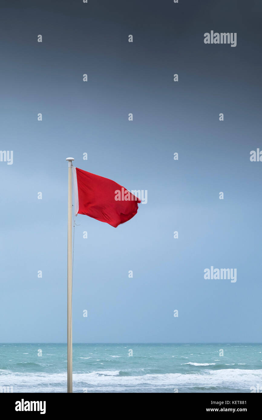 Bandiera rossa - una spia rossa bandiera volare con vento forte a Fistral Beach Newquay Cornwall. Foto Stock