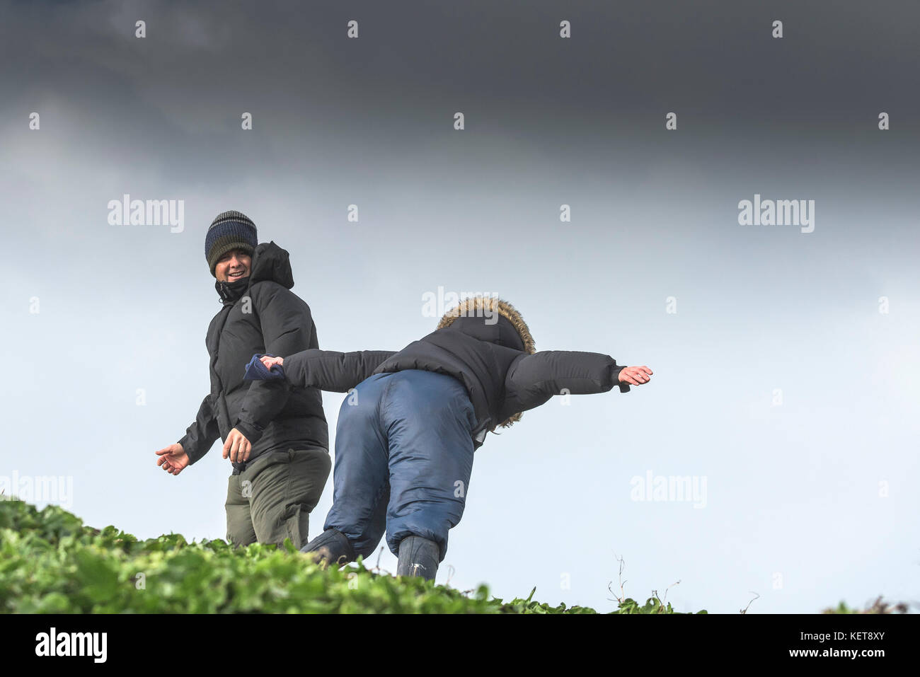 UK Weather Storm Brian - una coppia che si diverte a camminare nei venti della tempesta, mentre Storm Brian porta il tempo selvaggio alla costa della Cornovaglia settentrionale. Foto Stock