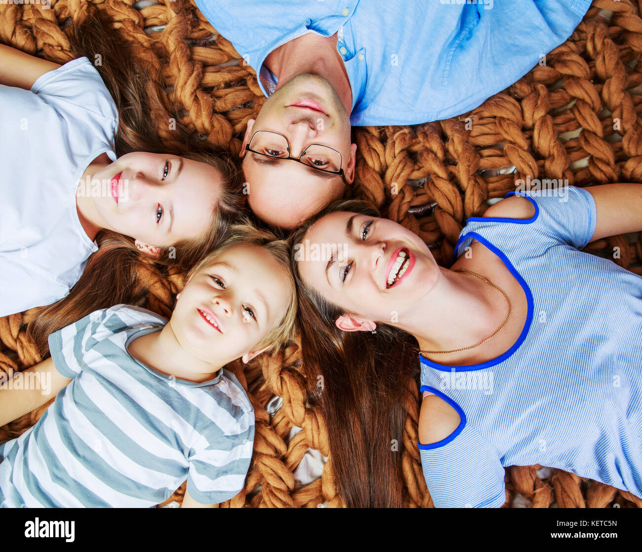 Felice giovani genitori con due bambini nel letto di casa Foto Stock