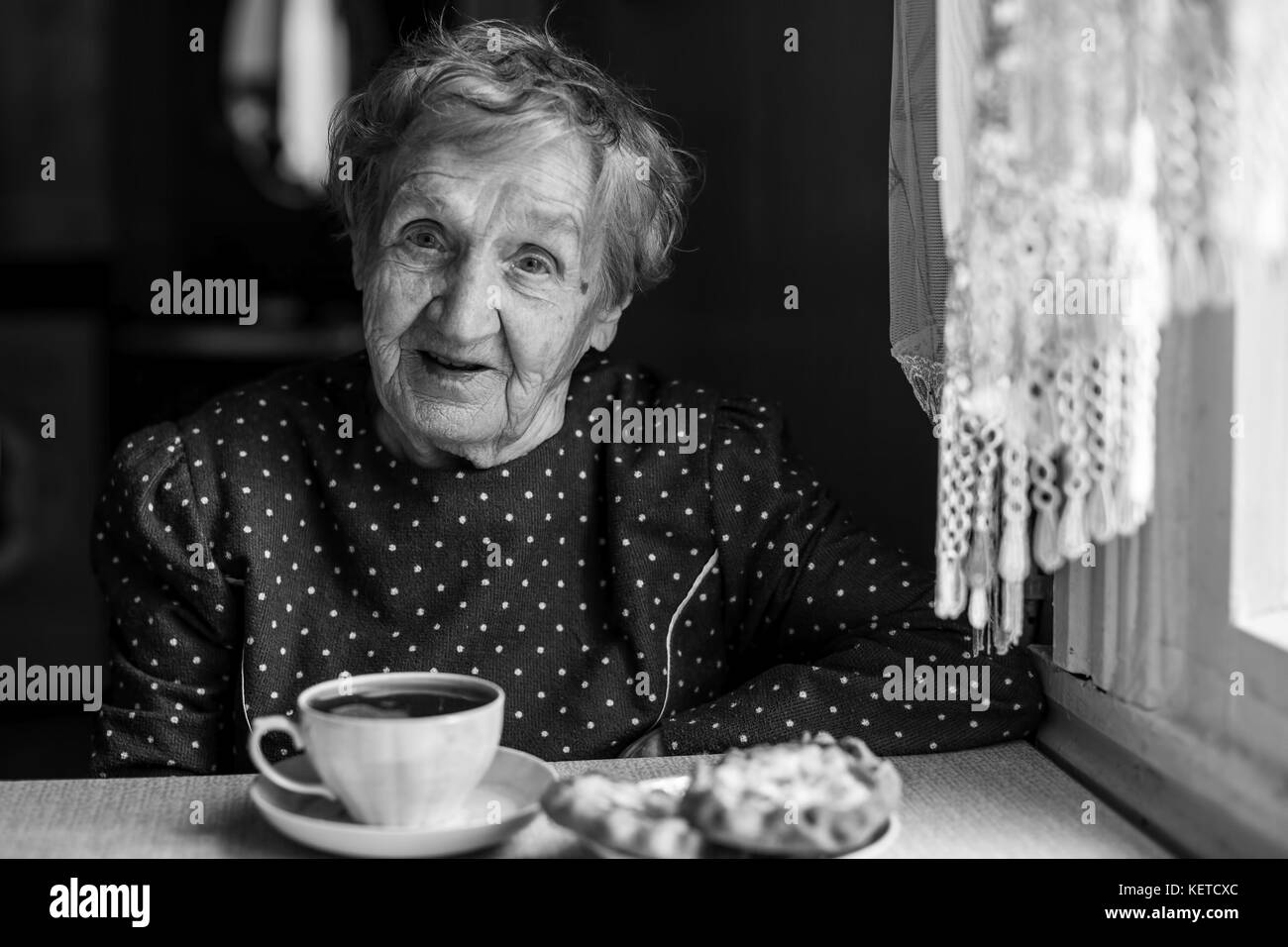 Donna anziana bere il tè nella sua casa. Foto Stock