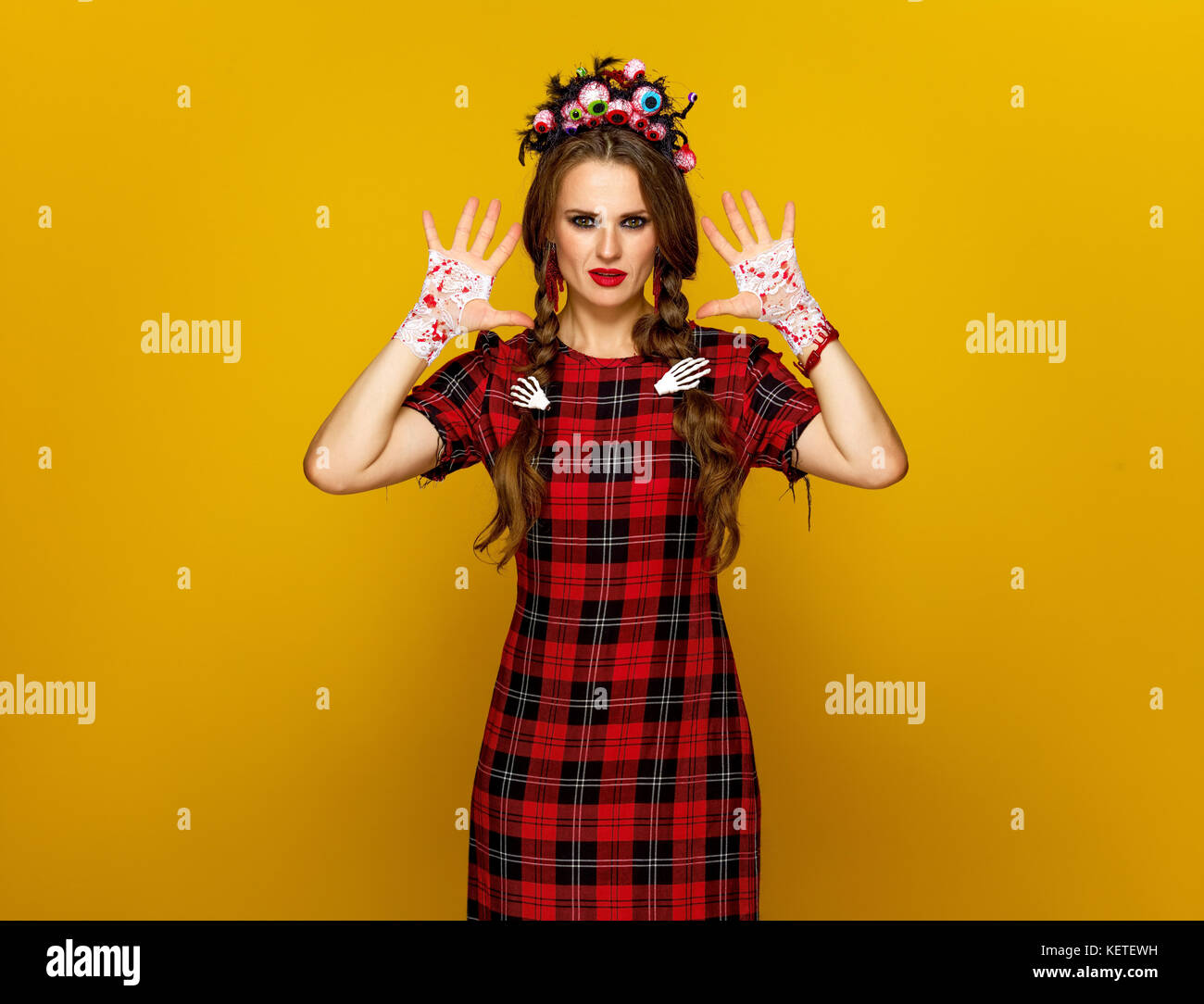 Colorato halloween. giovane donna in stile messicano costume di halloween isolato su sfondo giallo che mostra sanguinosa palms Foto Stock