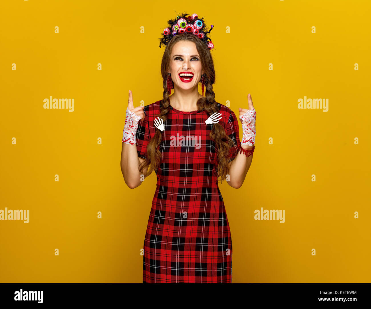 Colorato halloween. sorridente giovane donna in stile messicano costume di halloween su sfondo giallo rivolta verso l'alto a qualcosa Foto Stock