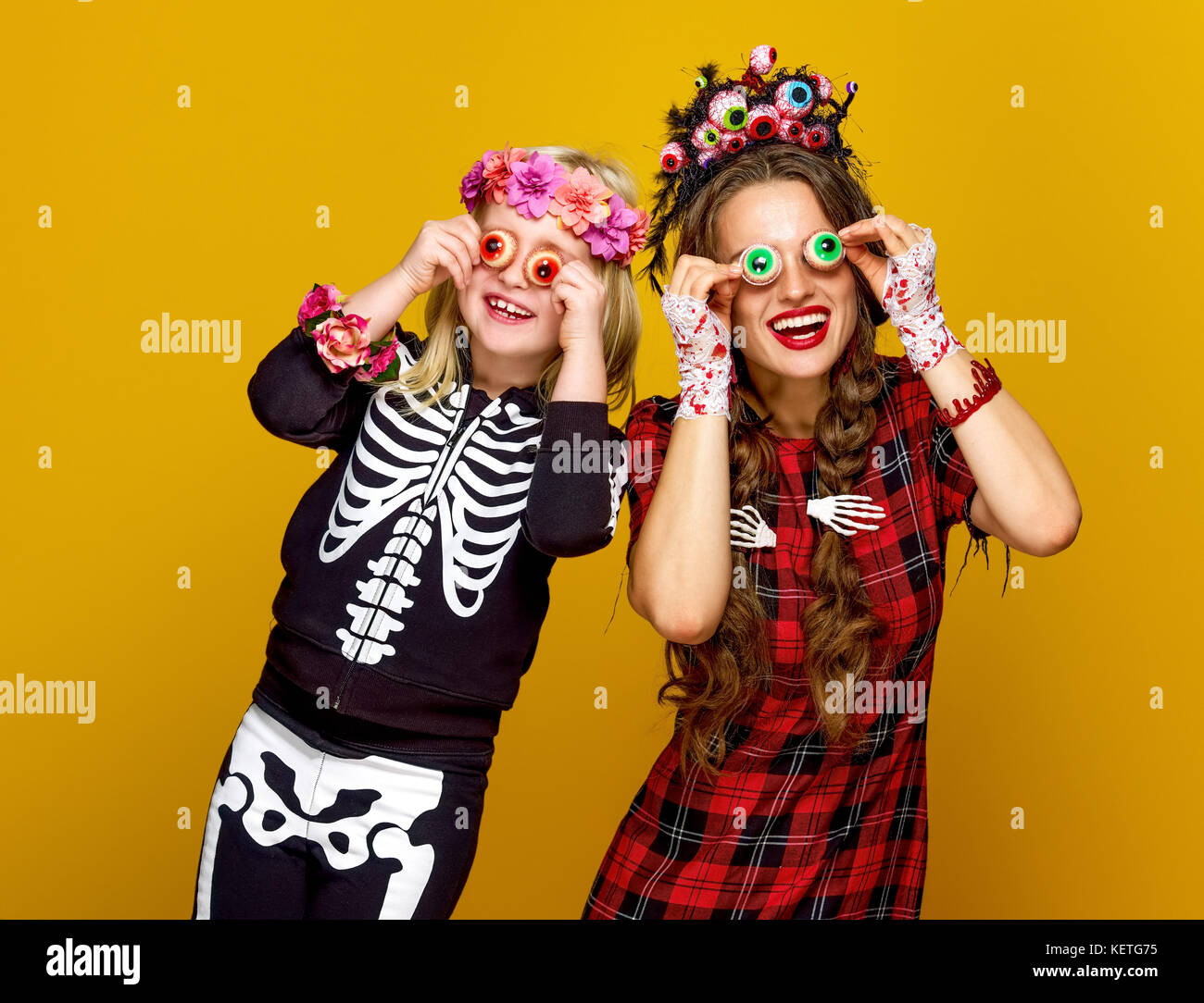 Colorato halloween. allegro moderno madre e figlia in stile messicano costume di halloween su sfondo giallo avente tempo di divertimento Foto Stock