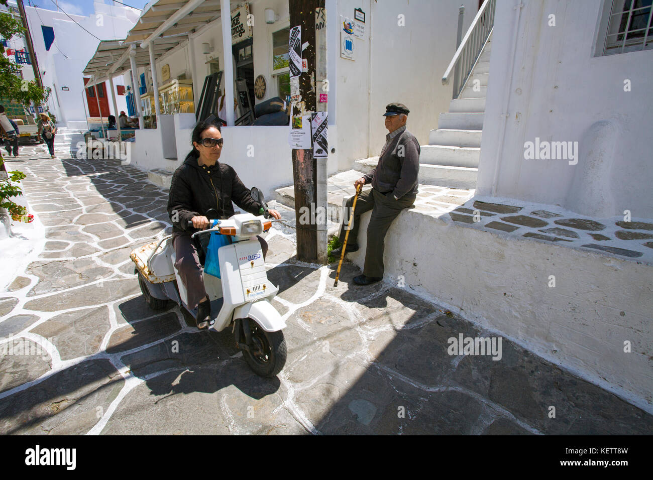 Donna locale su unità di scooter in uno stretto vicolo, Mykonos-town, Mykonos, Grecia Foto Stock