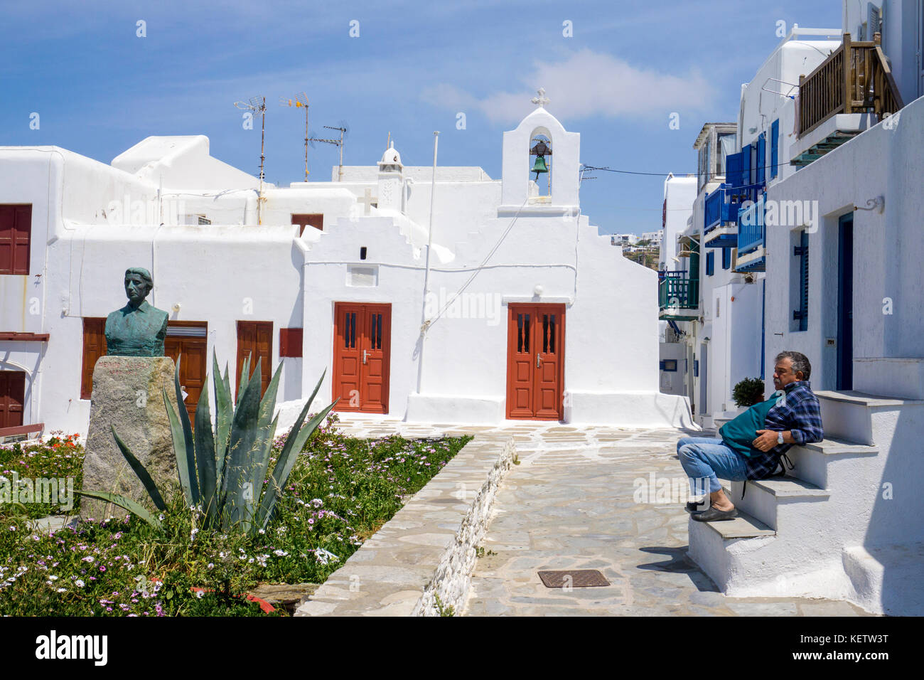Il greco uomo seduto sulla scalinata in corrispondenza di una cappella, Mykonos-town, Mykonos, Grecia Foto Stock