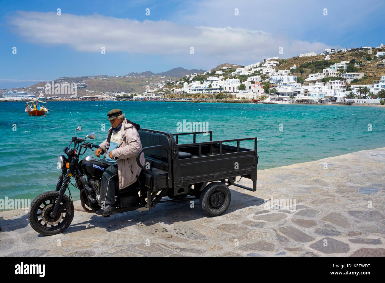 Il vecchio uomo su un nolo triciclo a motore al porto di Mykonos-town, Mykonos, Grecia Foto Stock