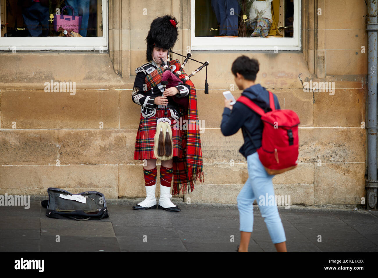 Street performance busker ai turisti di Edimburgo, Scozia, Canongate Royal Mile un vestito tradizionale piper suonare la cornamusa per denaro Foto Stock