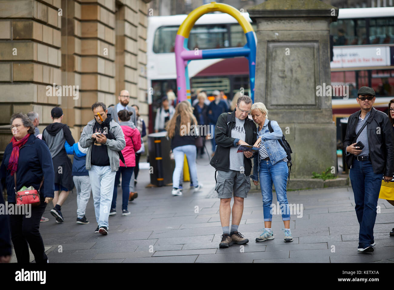 Edimburgo, Scozia, Canongate Royal Mile perduto turisti alla ricerca di una mappa vicino a un dipinto di barriera di sicurezza Foto Stock