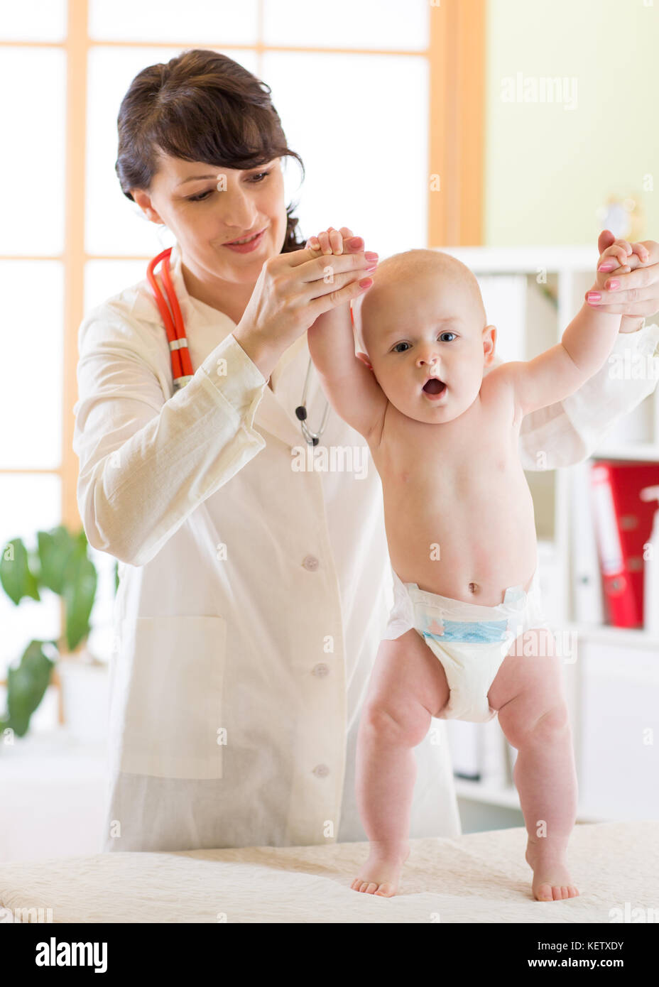Happy Baby a salute esame presso l'ufficio del medico pediatra. supporta il bambino mentre si sta in piedi Foto Stock