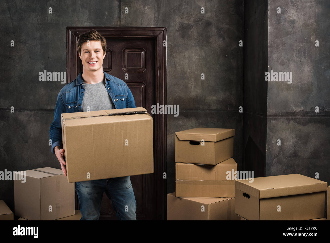 Uomo sorridente in movimento durante la nuova casa Foto Stock