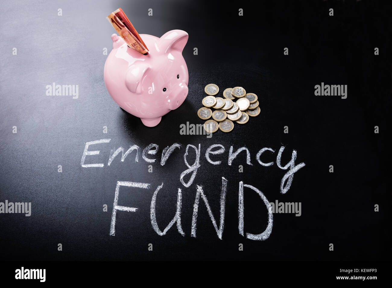 Fondo di emergenza testo di fronte a Piggybank con banconote e monete Foto Stock
