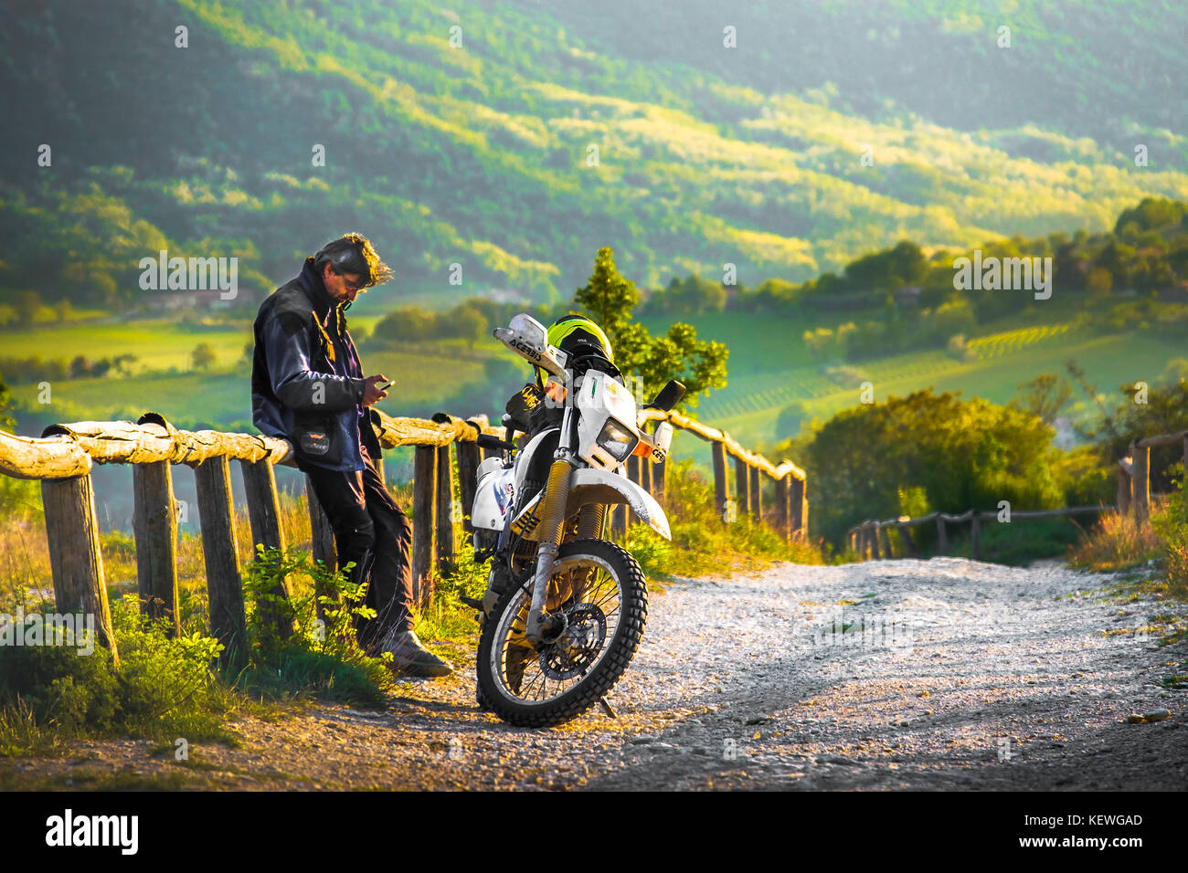 Su una strada fuori pista di motocross un ciclista resto al tramonto su una staccionata di legno nei colli euganei, Italia, 22 Apr 2017 Foto Stock