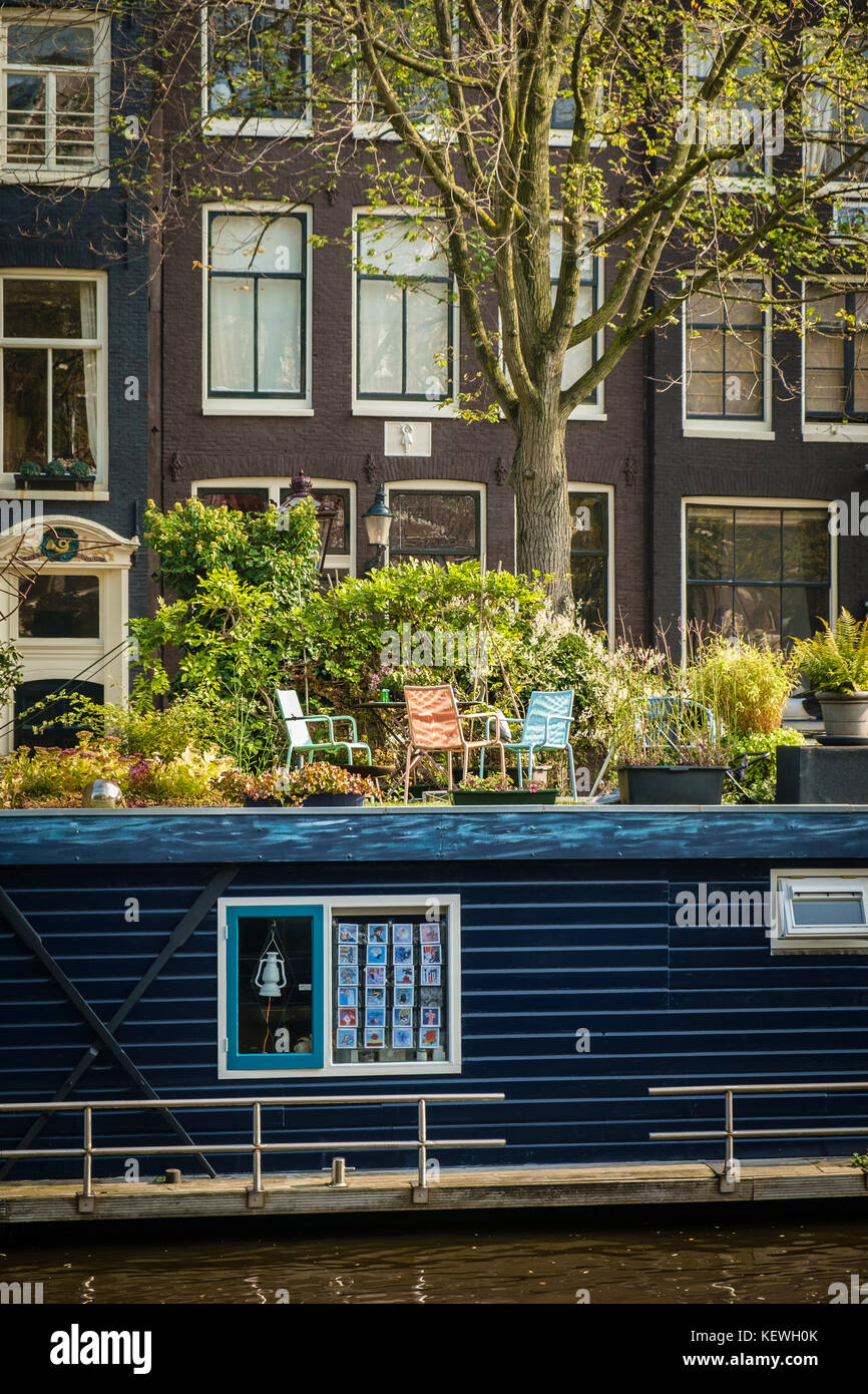 Terrazza soleggiata sul tetto di una casa galleggiante ormeggiata su un canale di Amsterdam. Foto Stock