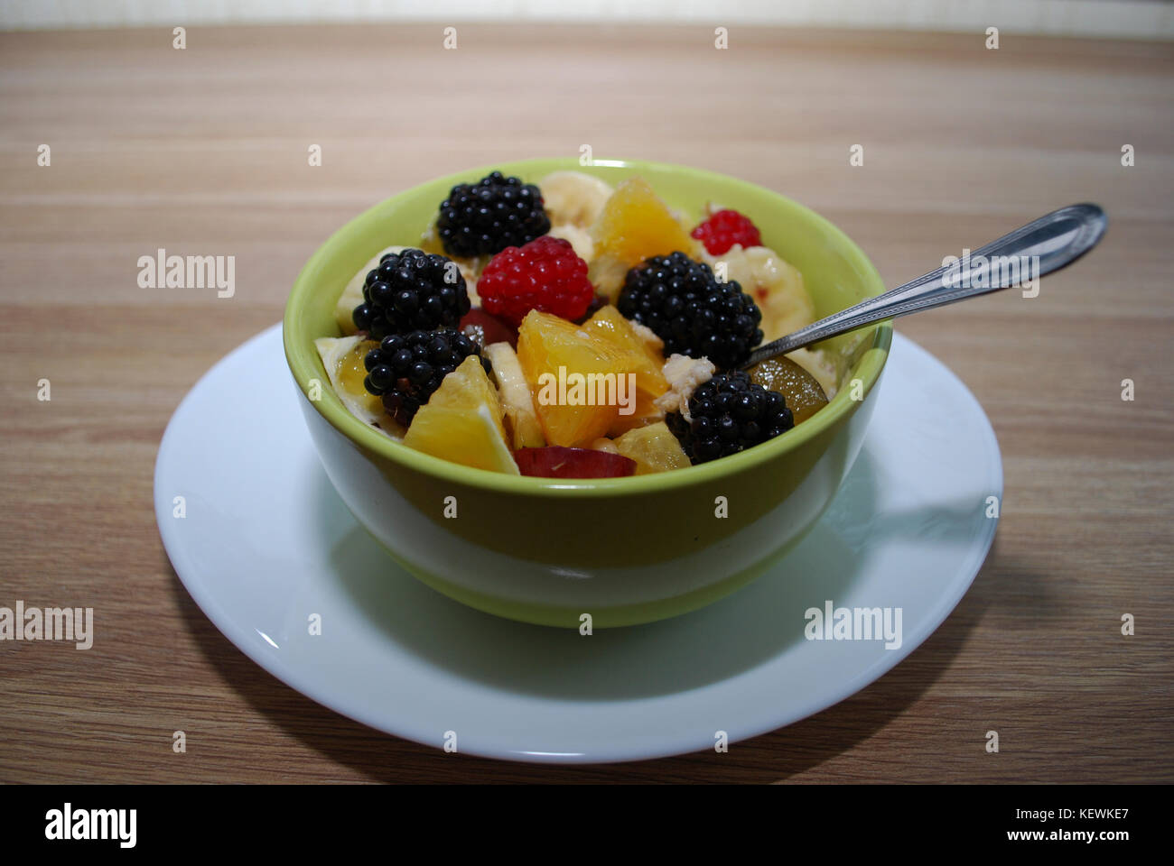 Frutta e bacche (insalata di arance, more, lamponi e banane) in un verde piatto. Foto Stock