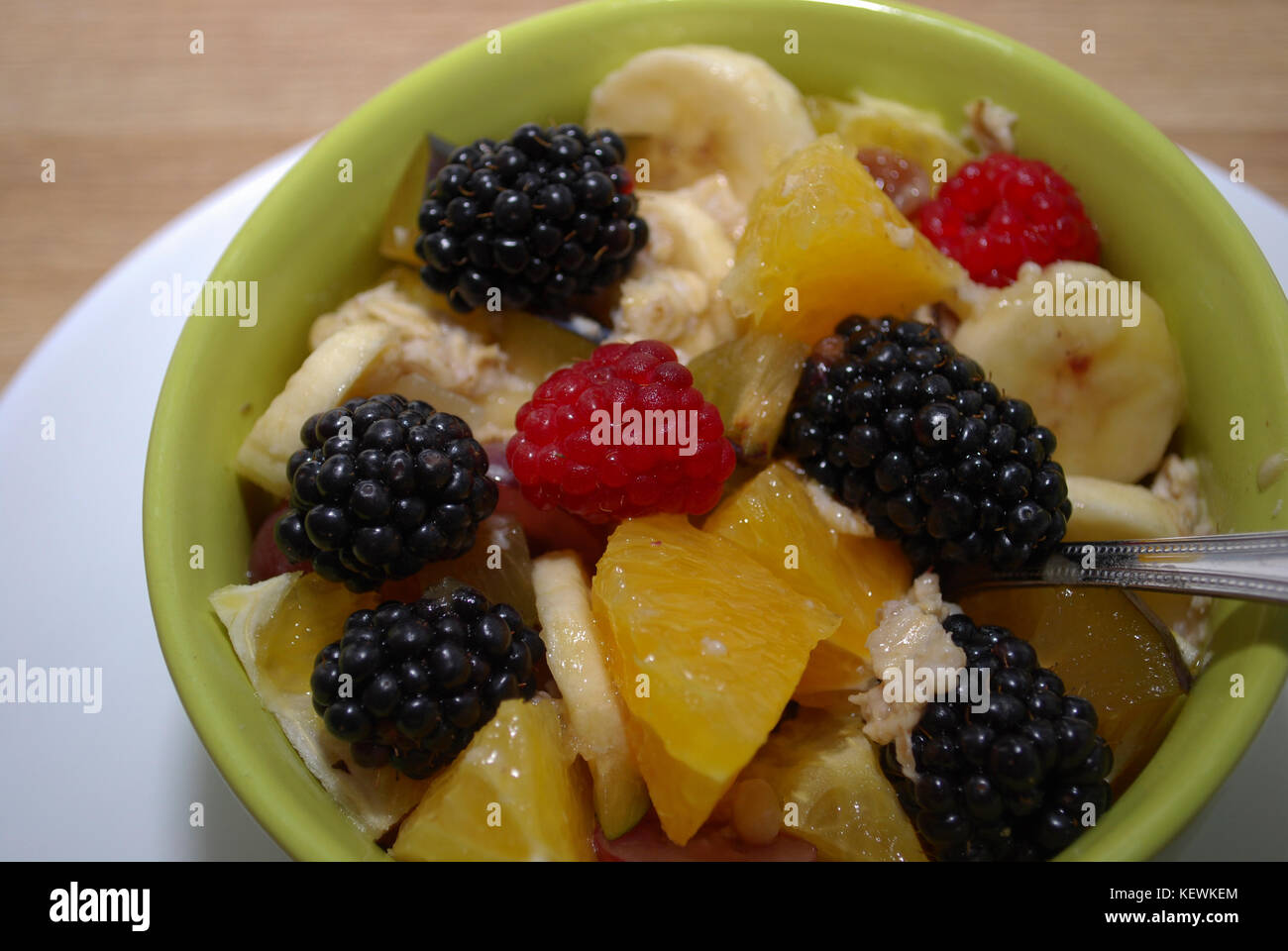 Frutta e bacche (insalata di arance, more, lamponi e banane) in un verde piatto. Foto Stock