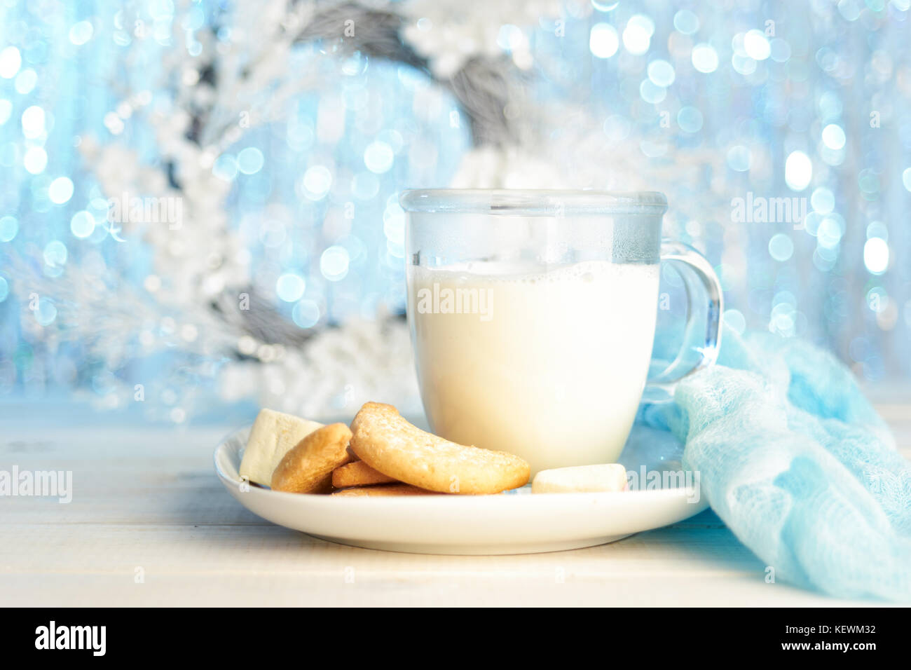 Tazza di vetro di latte caldo con i cookie su luce glitter sfondo per natale. copia spazio. Foto Stock