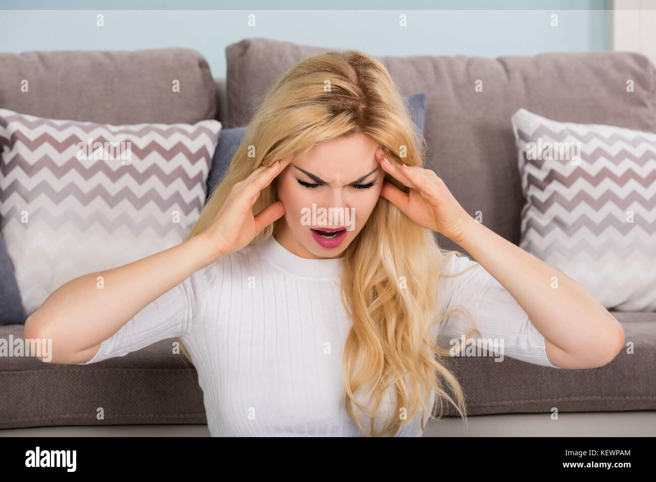 Ritratto di una giovane donna che soffre di mal di testa a casa Foto Stock