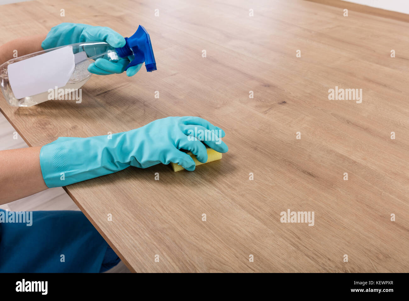 Donna che indossa guanti da cucina per la pulizia del piano di lavoro a casa Foto Stock