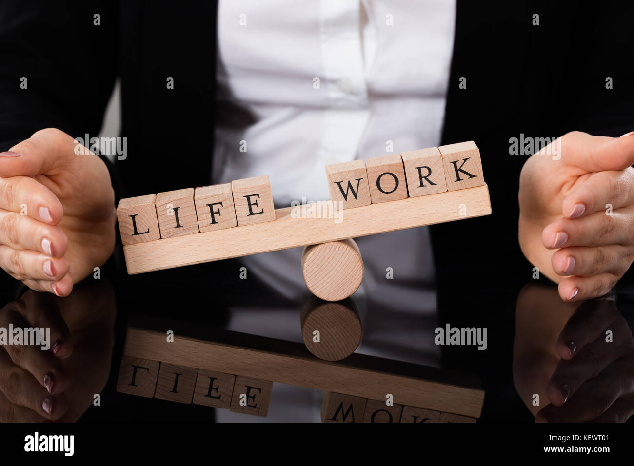 Imprenditrice mano coprendo equilibrio tra vita e lavoro su altalena a tavola Foto Stock