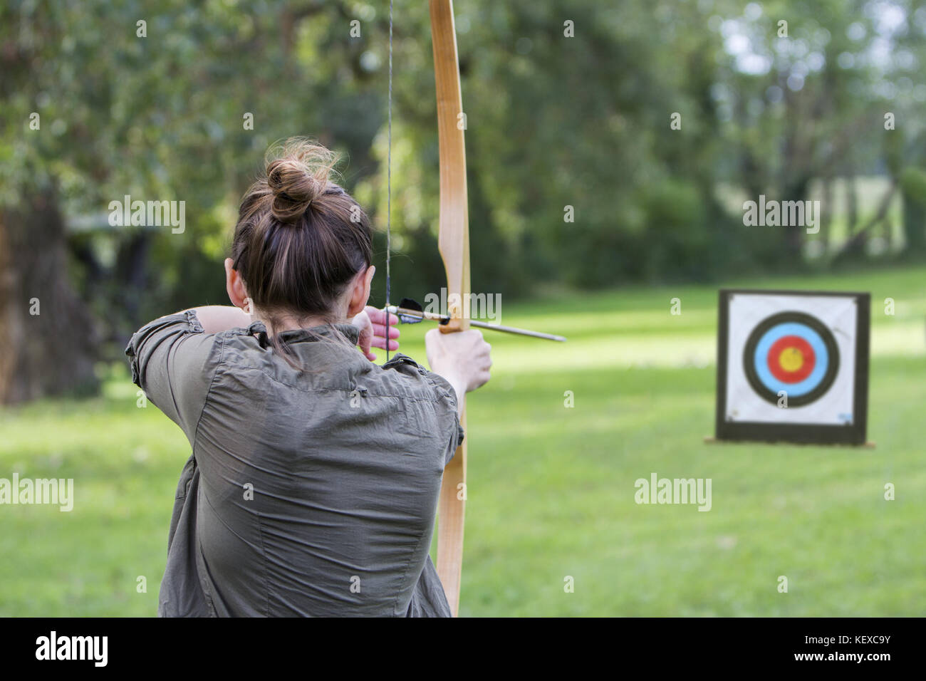 Donna arciere per utilizzare un arco e frecce e sparare a un bersaglio Foto Stock