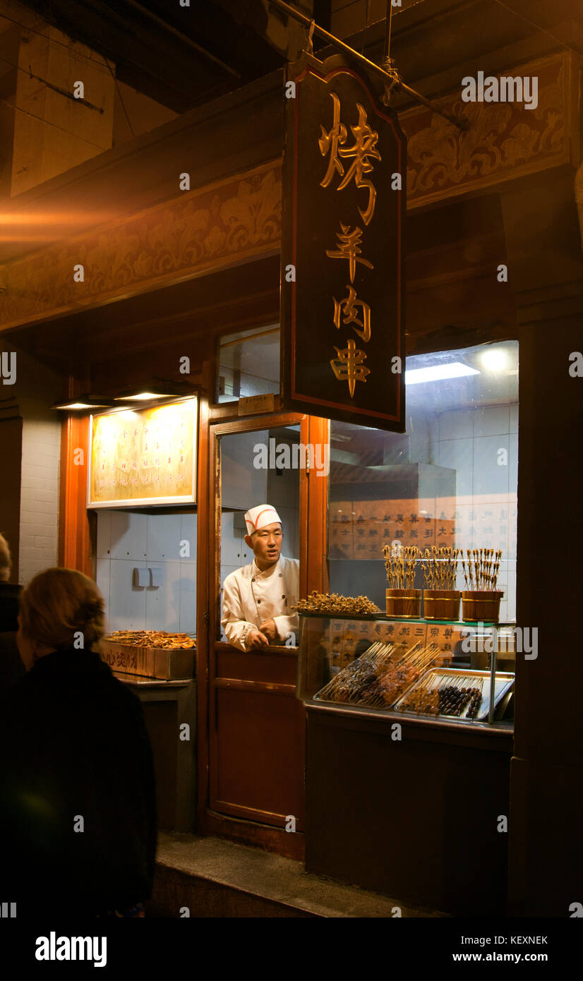 Fornitore in cappelli chef presso il negozio di alimentari al mercato notturno, Pechino, Cina Foto Stock