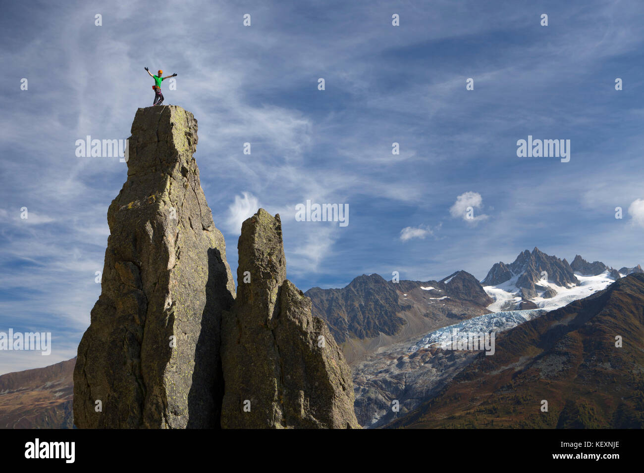 Un arrampicatore di montagna che si erge su una cima alta sopra Chamonix nelle Alpi francesi. Il ghiacciaio Argentiere è sullo sfondo. Foto Stock