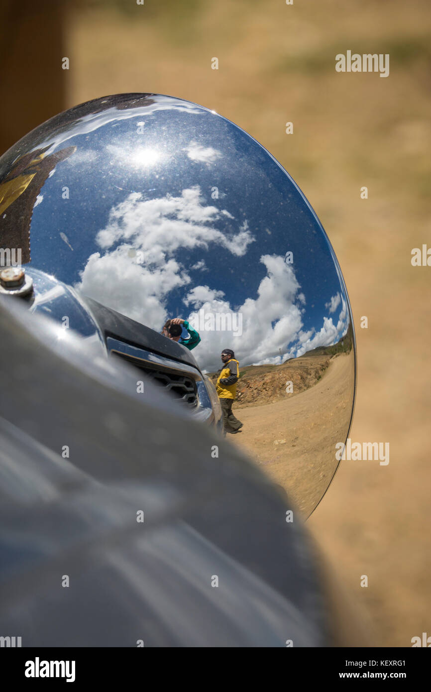 Fotografia con la riflessione della persona nel faro della vettura durante la guida nelle Ande peruviane, Perù Foto Stock