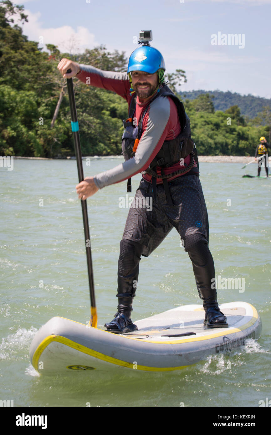 Fotografia dell'uomo paddleboarding in stand-up paddleboard, Amazzonia peruviana, Parco Nazionale del Manu, Perù Foto Stock
