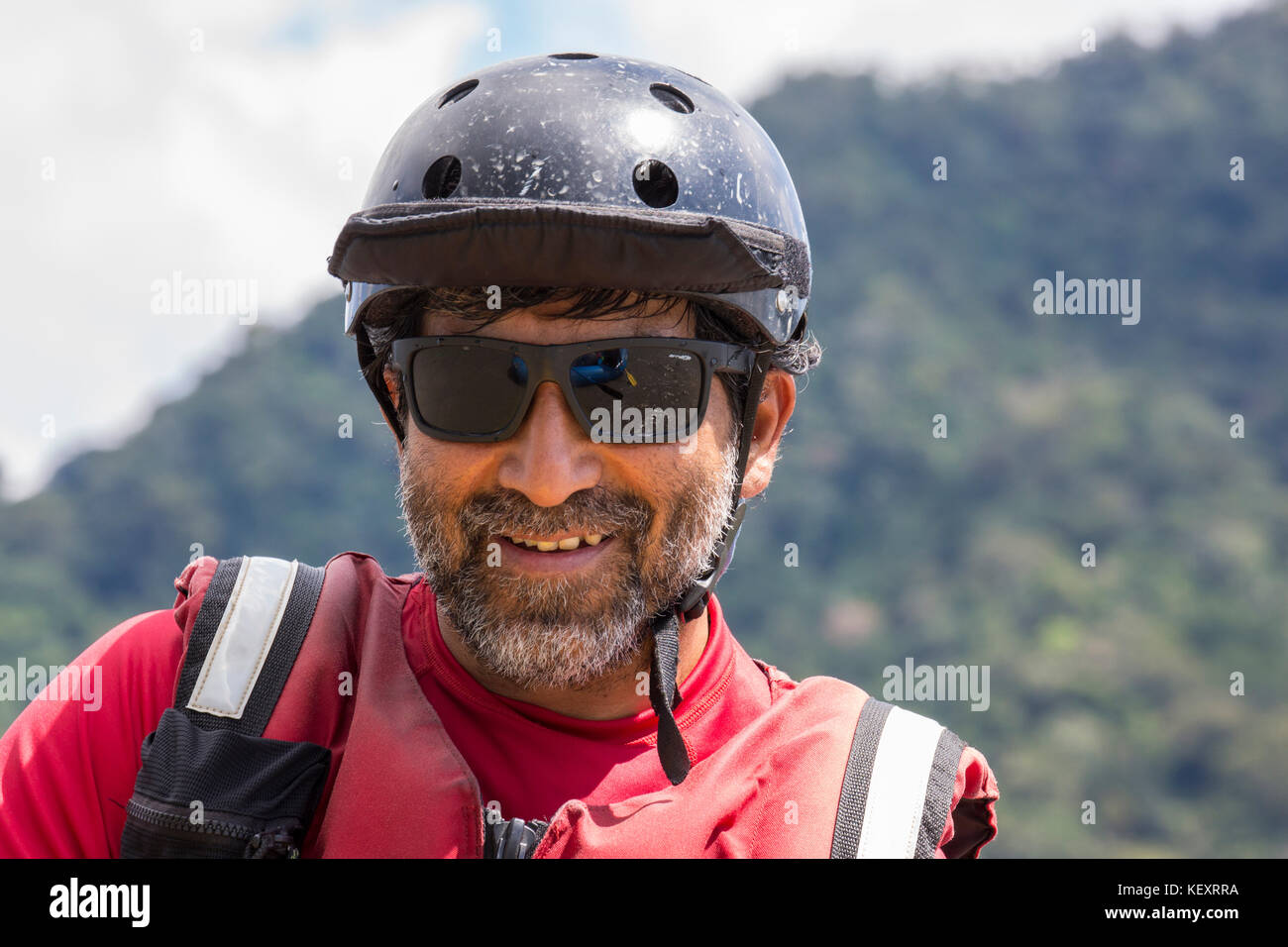 Uomo con casco sorrisi mentre sulle rive di un fiume spedizione nel Parco Nazionale del Manu, Perù. Foto Stock