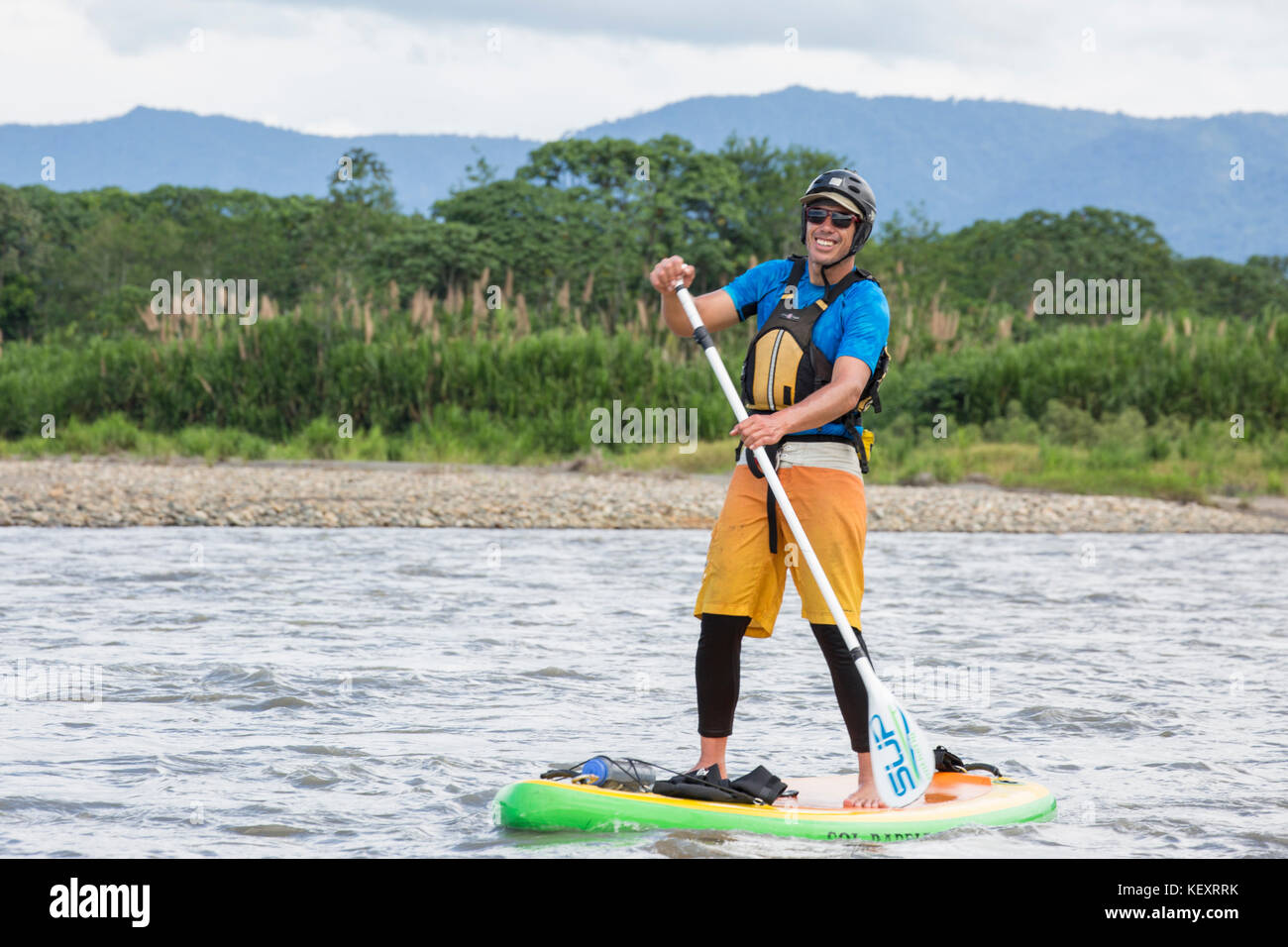 Uomo in stand-up paddleboard (SUP) sul alto (superiore) di Madre de Dios River nella giungla dell'Amazzonia peruviana, Perù. Foto Stock