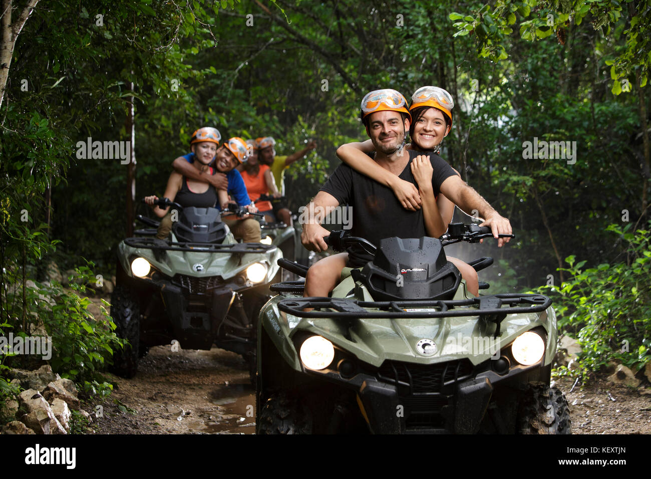 Le coppie che abbraccia mentre cavalcate quad bikes in emozioni Parco nativo, Quintana Roo, Messico Foto Stock