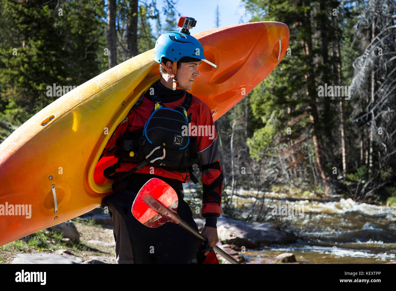 Vista frontale del giovane uomo in piedi con il kayak in foresta, Uinta Mountains, Utah, Stati Uniti d'America Foto Stock