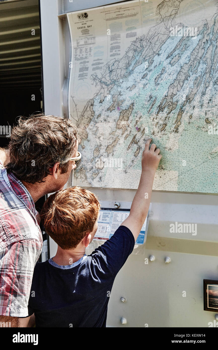 Padre e figlio esaminano la mappa appesa a muro, Portland, Maine, USA Foto Stock