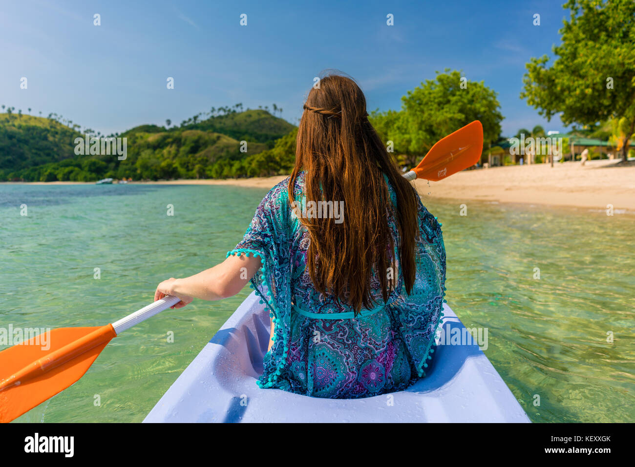 Giovane donna paddling una canoa lungo la riva di un idilliaco islan Foto Stock