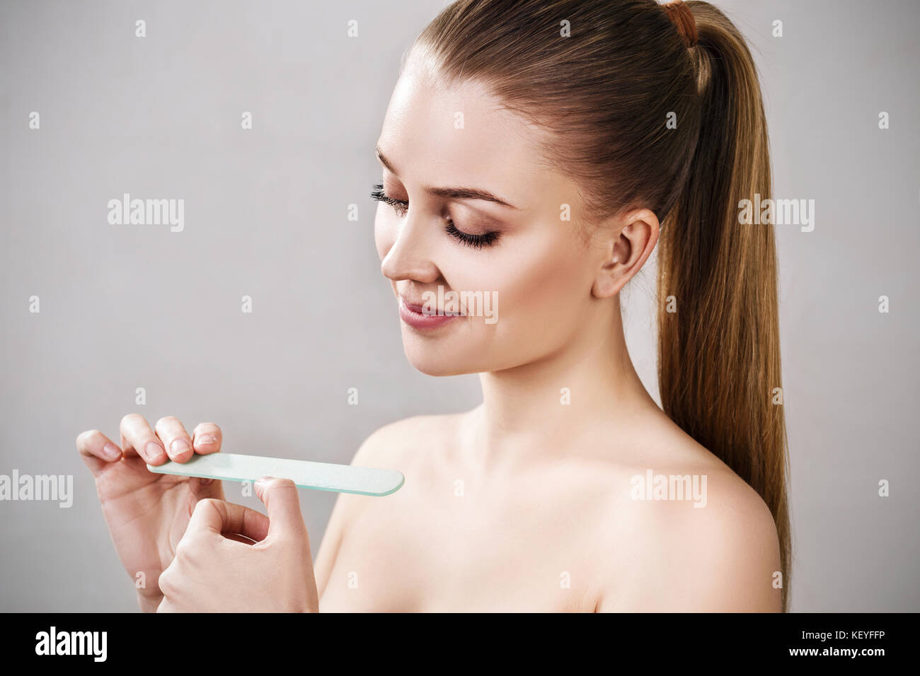 Giovane donna facendo manicure con lima per unghie. Foto Stock