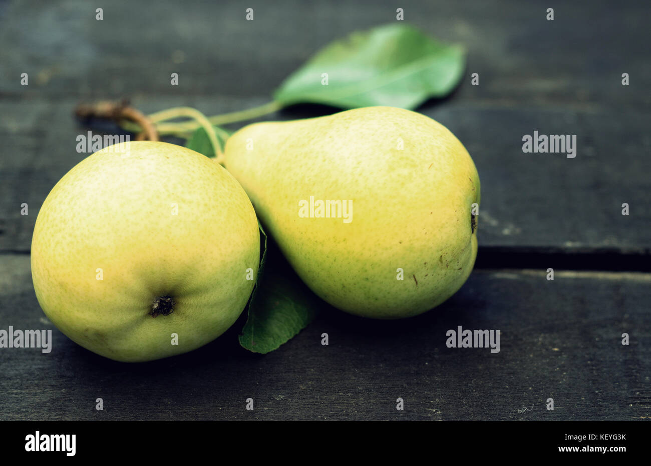 Due pere giallo al buio su un sfondo di legno Foto Stock
