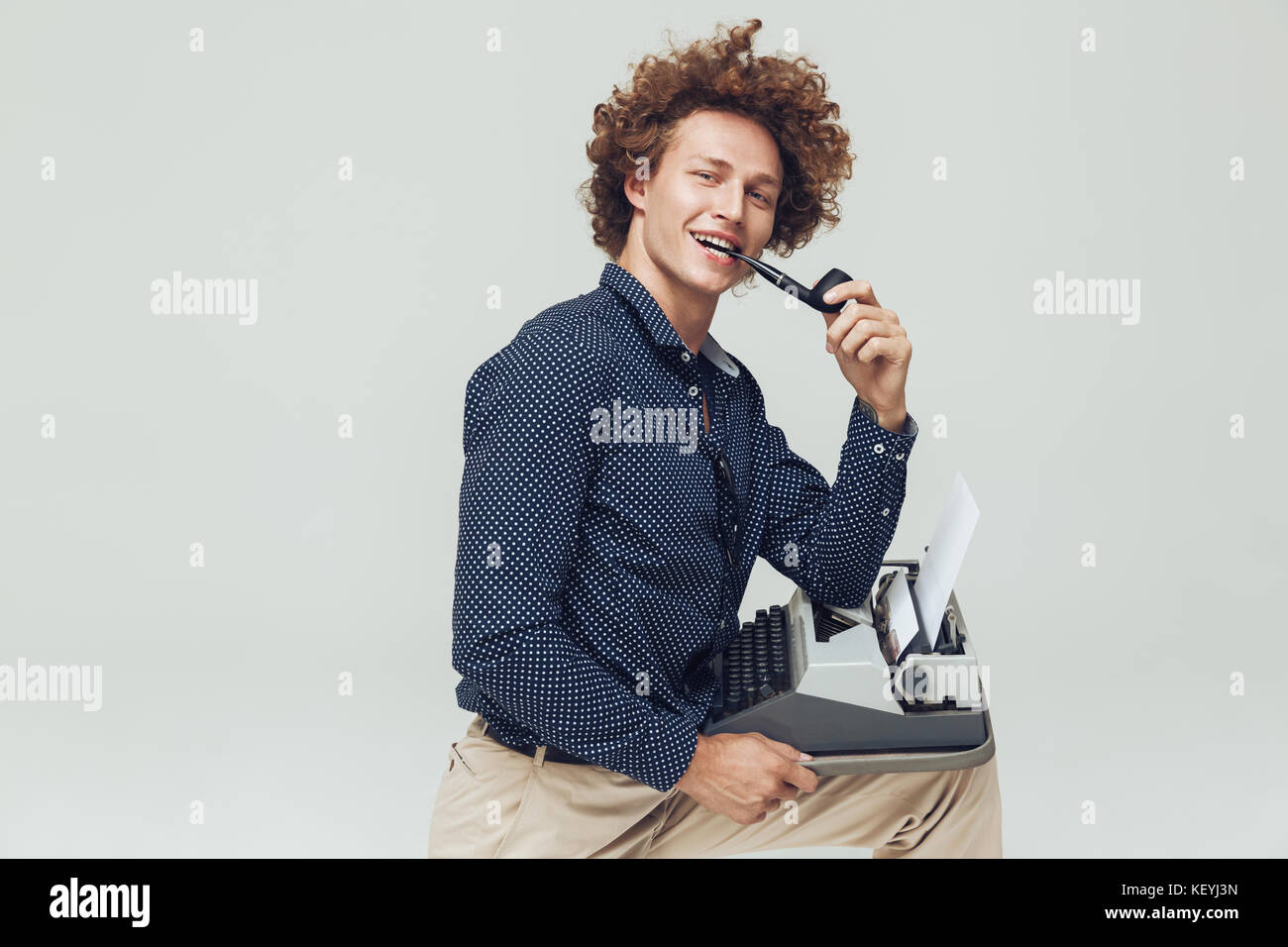 Foto di giovani felici retrò uomo vestito in maglietta e seduta in posa isolato. Guardando la telecamera con il tubo tenendo i nastri inchiostratori per macchine da scrivere. Foto Stock