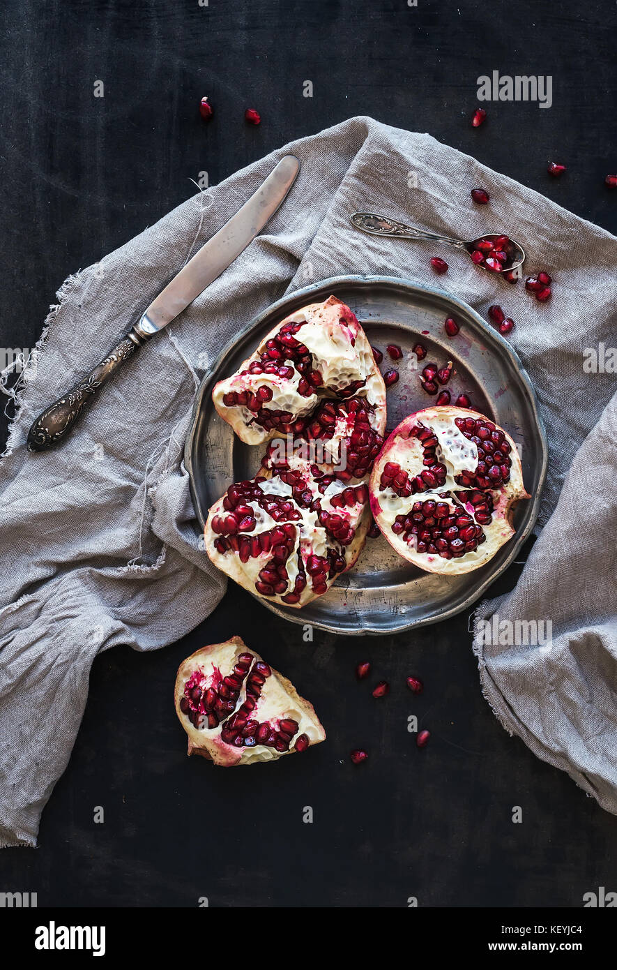 Rosso maturo pelato melograno rustico sulla piastra di metallo e beige asciugamano da cucina Foto Stock