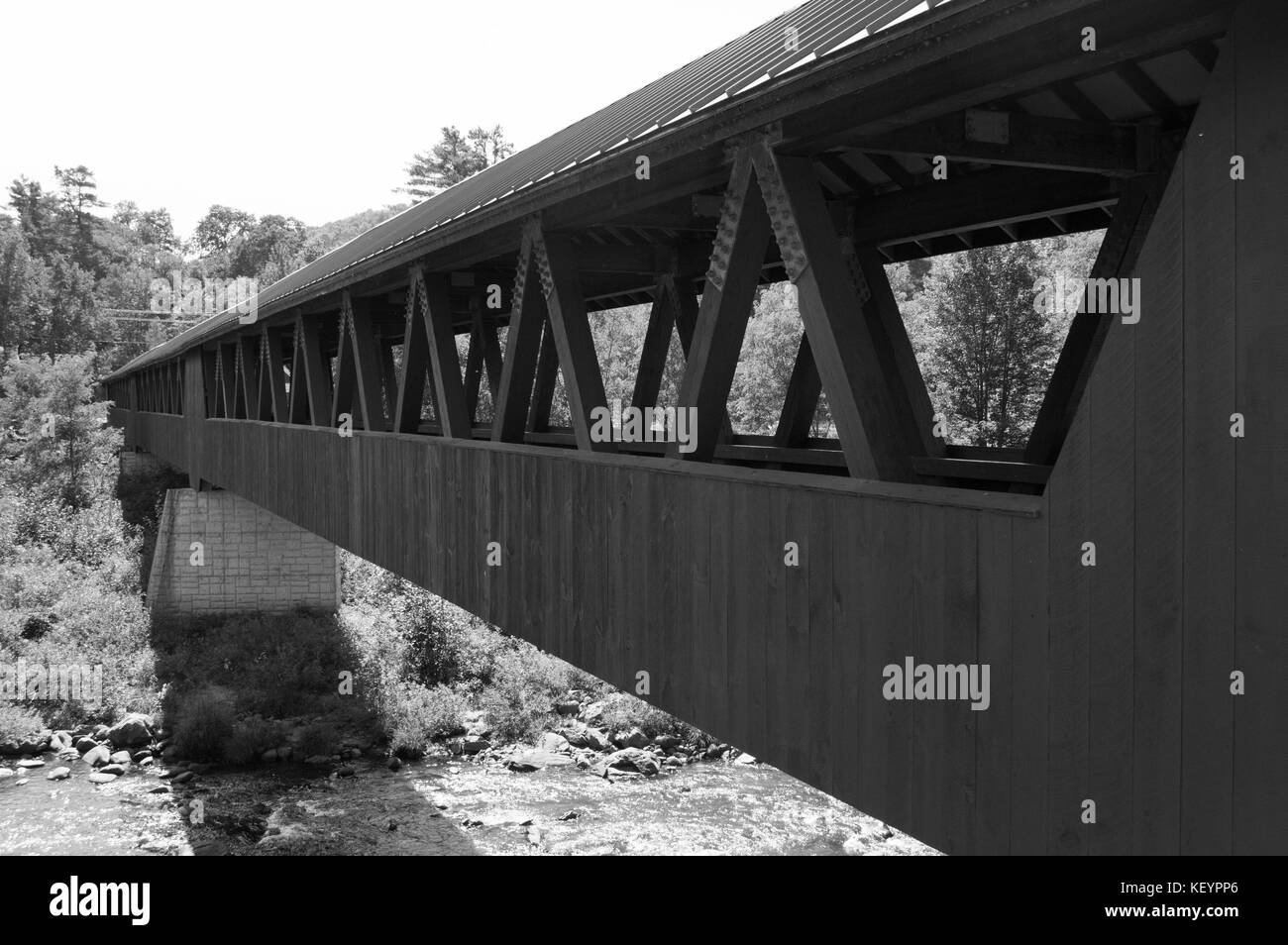 Un vecchio new Hampshire ponte attraversa un flusso occupato nei boschi. Foto Stock