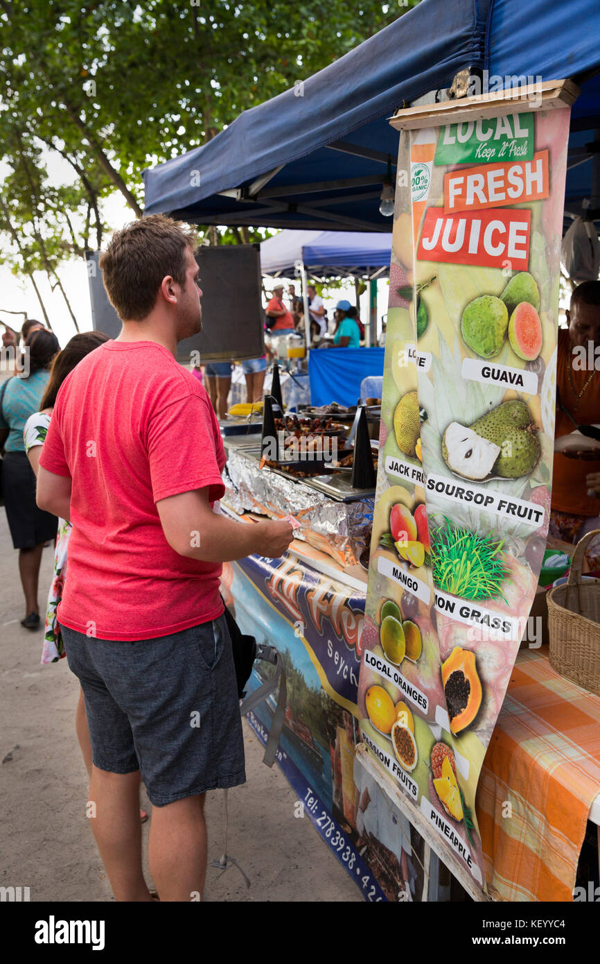 La Seychelles, Mahe, Beau Vallon, mercato turistico, uomo al succo di frutta fresca in stallo Foto Stock