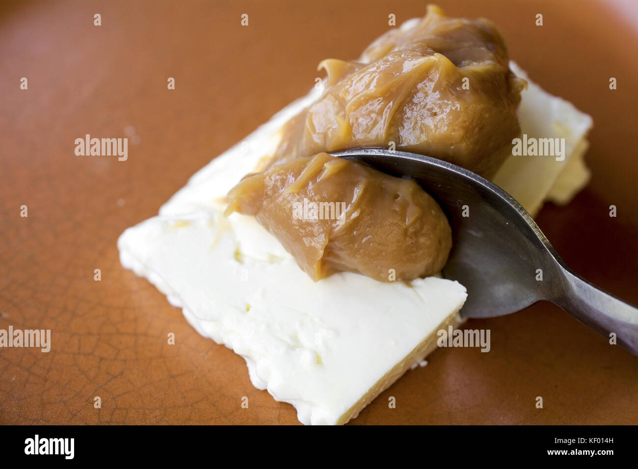 Primo piano sul cucchiaio un prelievo che serve di caramel cream (doce de Leite) con formaggio bianco (queijo de minas), un deserto brasiliano, visto dal lato, su Foto Stock