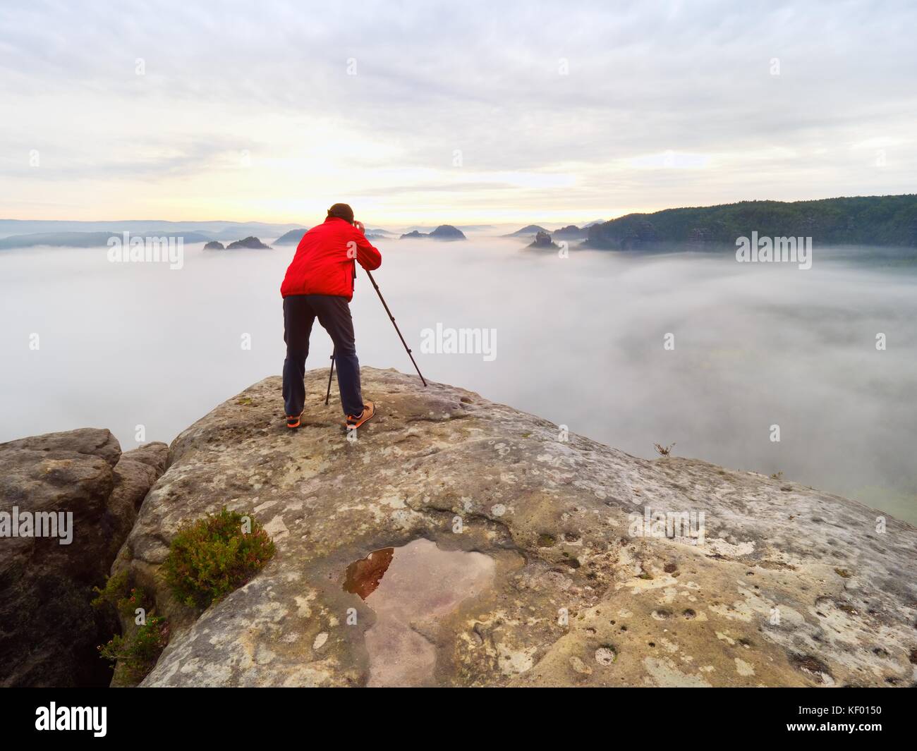 Fotografo elaborazione immagine con occhio sul mirino. appassionati di fotografia Godetevi il lavoro di natura caduta sulla vetta rocciosa. paesaggio da sogno, misty sunrise in un Foto Stock