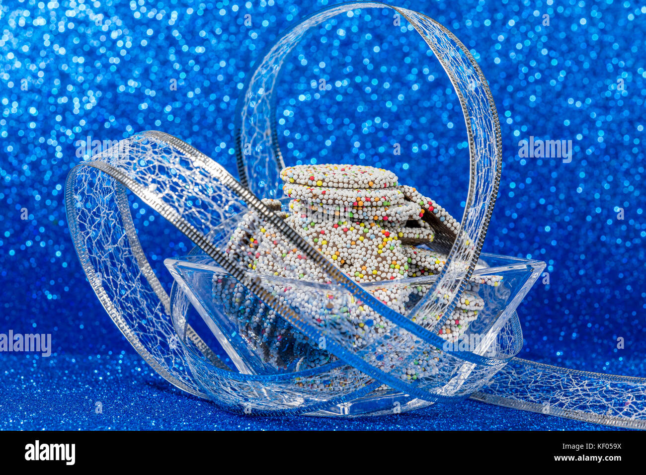 Cioccolato colorato anelli nella ciotola con decorazione di Natale su sfondo blu Foto Stock