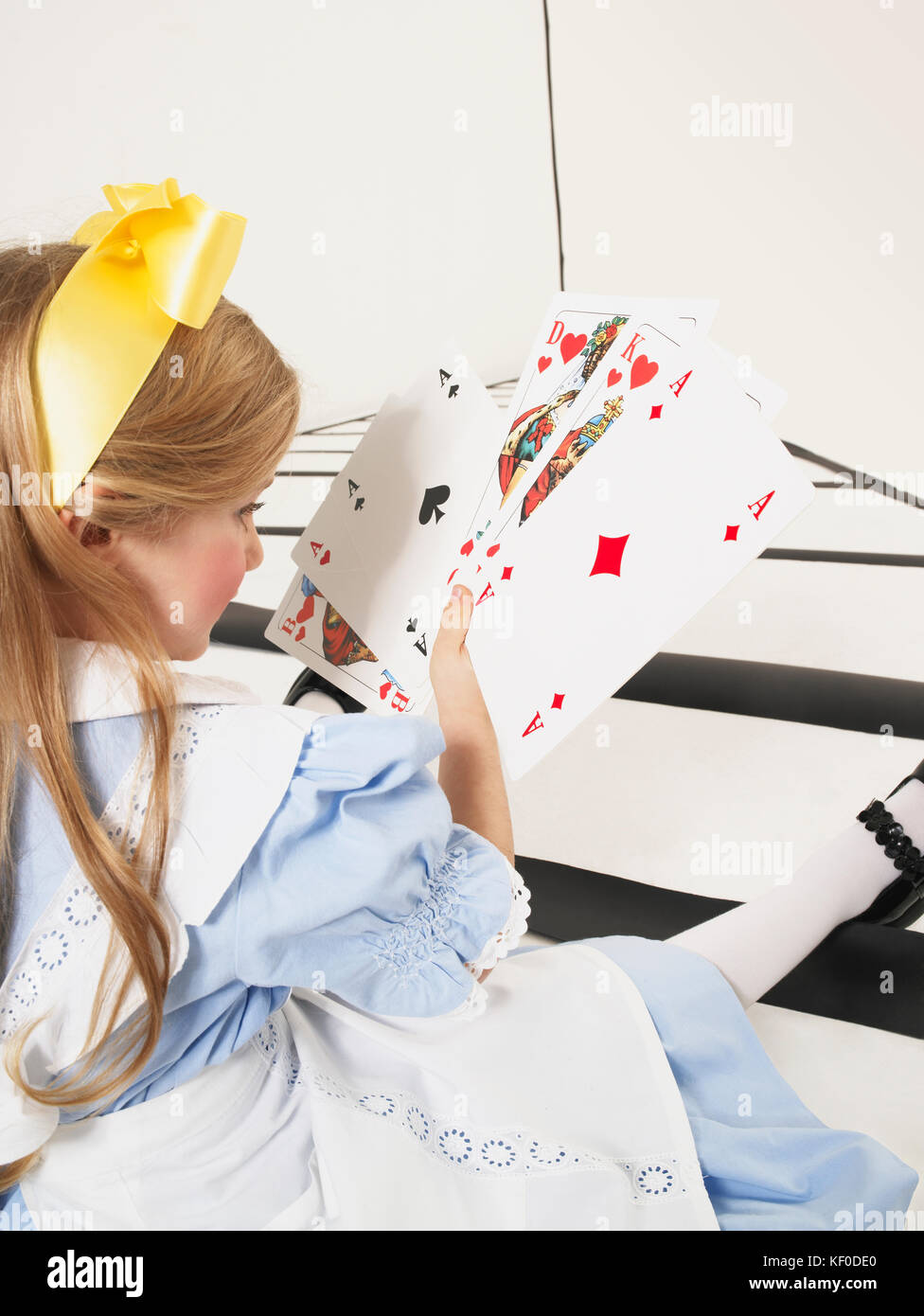 Bambina vestito come Alice nel paese delle meraviglie con grandi carte da  gioco Foto stock - Alamy