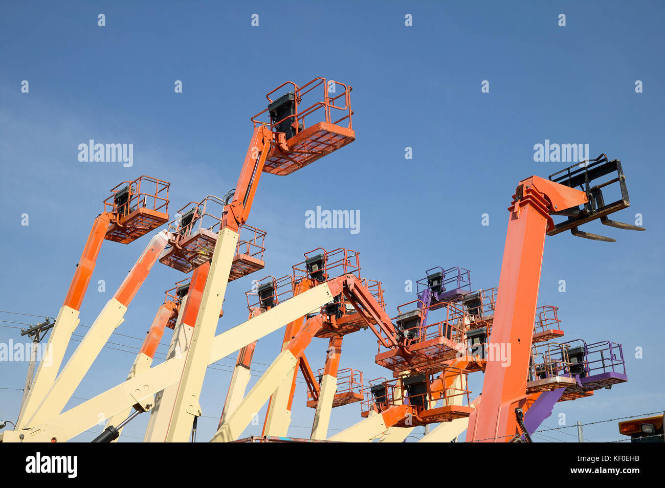 A basso angolo di visione di un arancio grande gruppo di piattaforma di lavoro aerea contro il cielo blu chiaro Foto Stock