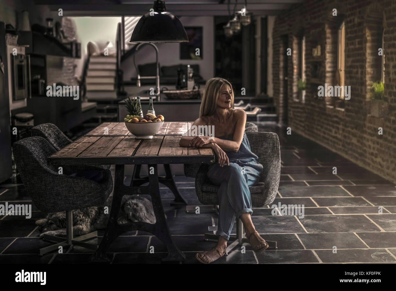 Donna seduta al tavolo da pranzo nella sua casa di campagna, pensando Foto Stock